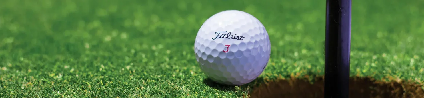 Bild von einem Golfball, der neben einem Loch auf dem Golfplatz von Fehmarn liegt