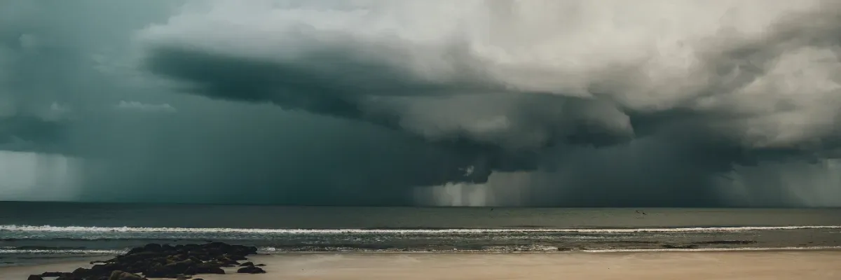 Dunkle Regenwolken über der Ostsee vor einem Strand auf Fehmarn