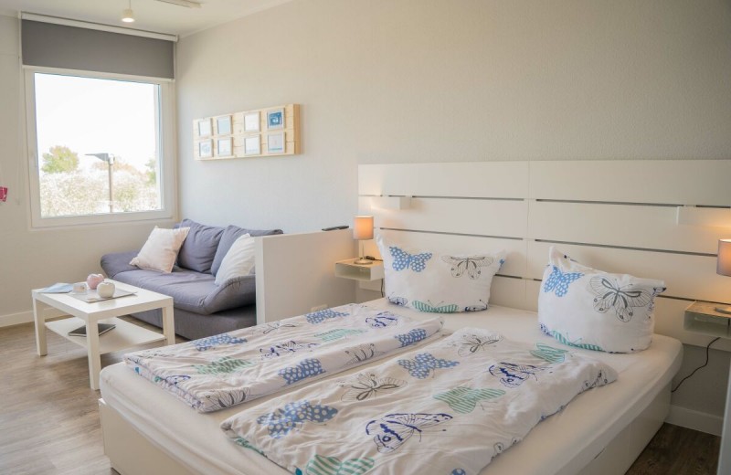 Doppelbett und gemütliche Couch in der Ferienwohnung mit Blick auf den Yachthafen auf Fehmarn
