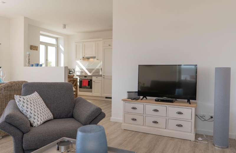 TV und Sessel mit Blick Richtung Küche in der Ferienwohnung auf Fehmarn
