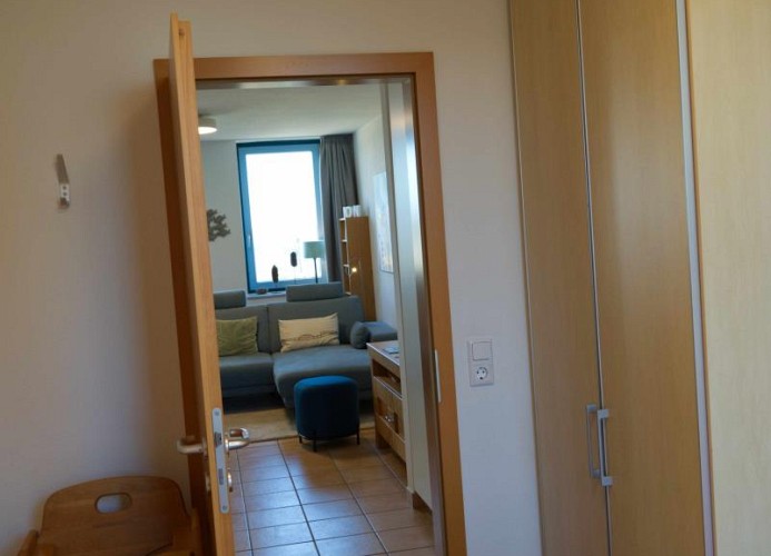 Blick aus dem Schlafzimmer in das Wohnzimmer der Ferienwohnung mit Hund