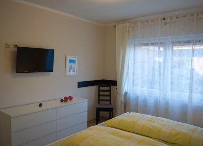 Kommode und TV am Fußende des Doppelbetts in der Ferienwohnung in Landkirchen