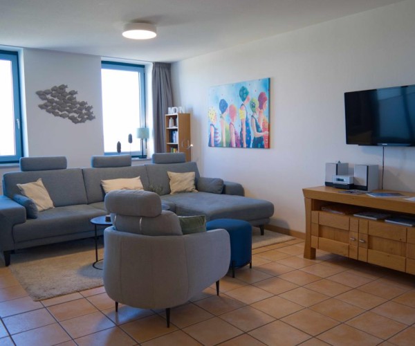 Wohnzimmer mit Couch und Sessel in der Ferienwohnung in der Strandburg auf Fehmarn