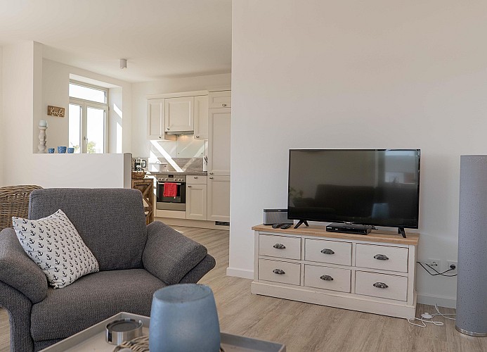 TV und Sessel mit Blick Richtung Küche in der Ferienwohnung auf Fehmarn