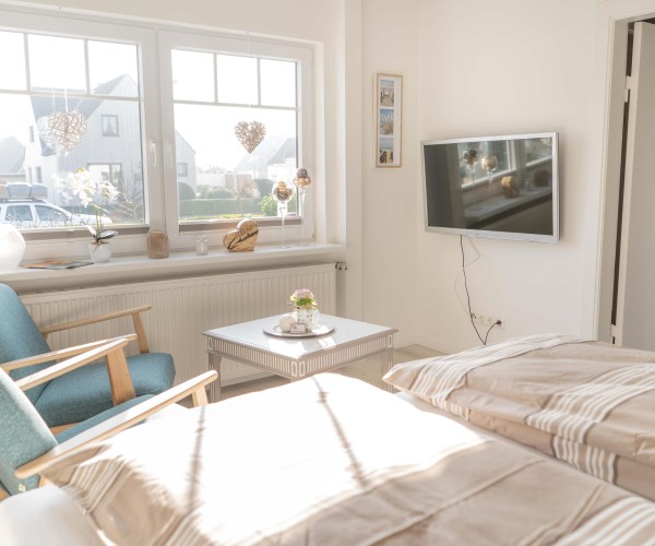 Schlafzimmer mit TV und Sesseln in der Ferienwohnung Inselblume 66 auf Fehmarn