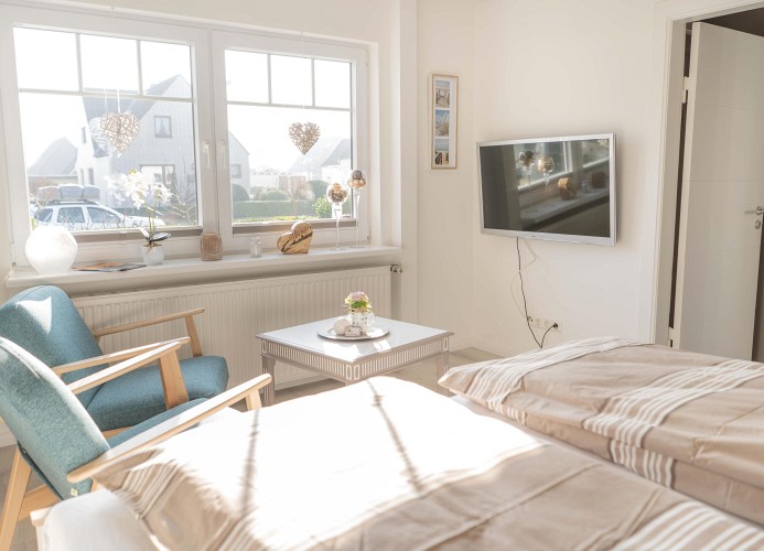 Schlafzimmer mit TV und Sesseln in der Ferienwohnung Inselblume 66 auf Fehmarn