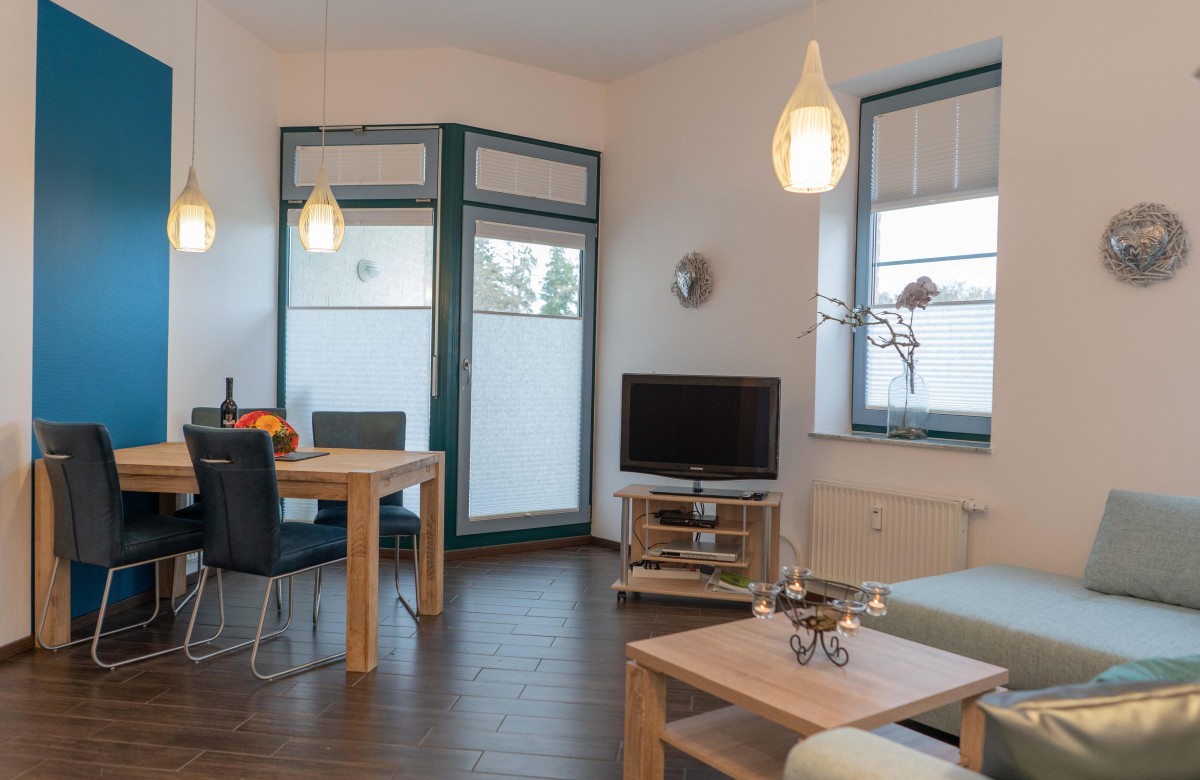 Esstisch mit TV und Couch im Wohnzimmer der Ferienwohnung direkt am Südstrand in Burgtiefe