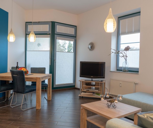 Esstisch mit TV und Couch im Wohnzimmer der Ferienwohnung direkt am Südstrand in Burgtiefe