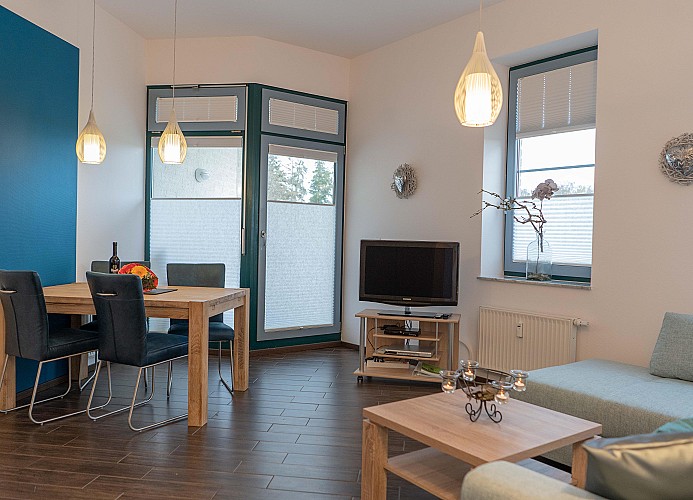 Esstisch mit TV und Couch im Wohnzimmer der Ferienwohnung direkt am Südstrand in Burgtiefe