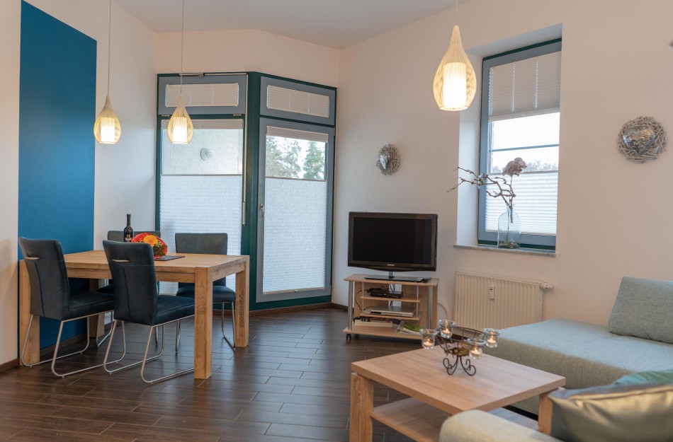 Esstisch mit TV und Couch im Wohnzimmer der Ferienwohnung direkt am Südstrand in Burgtiefe
