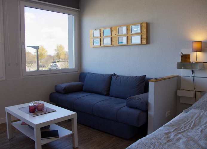 Doppelbett und gemütliche Couch in der Ferienwohnung mit Blick auf den Yachthafen auf Fehmarn