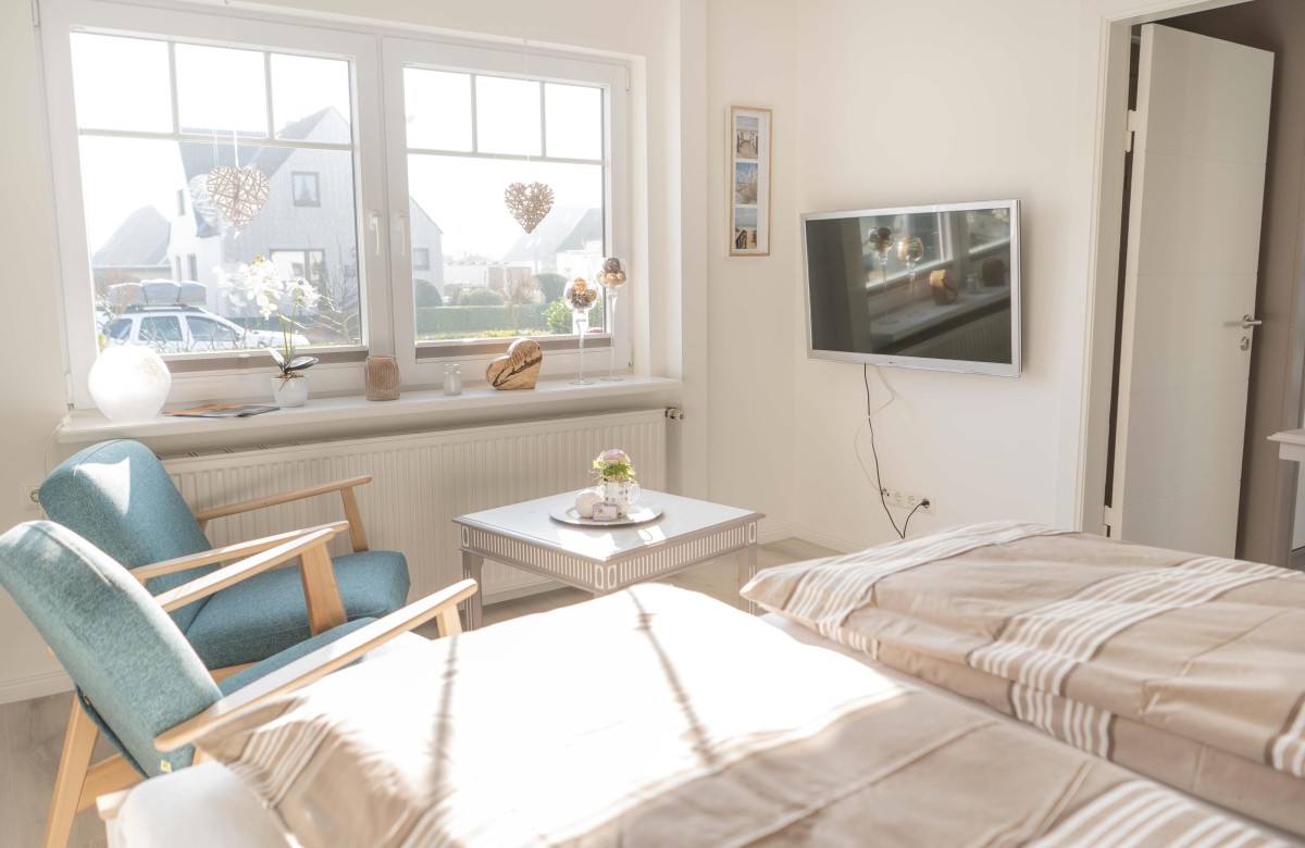 Schlafzimmer mit TV und Sesseln in der Ferienwohnung Inselblume 66 auf Fehmarn